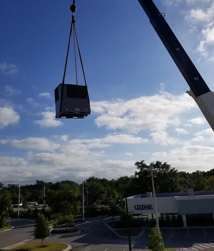 Crane lifting a new commercial HVAC unit onto a commercial building during an HVAC installation project in Palm Coast FL
