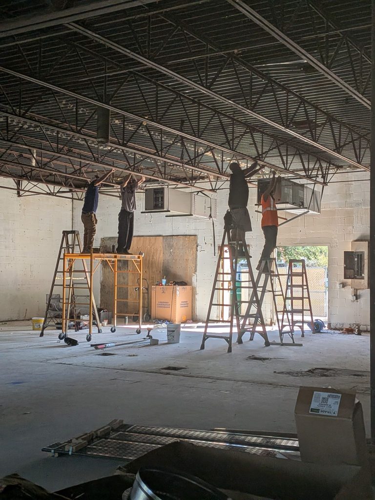 HVAC technicians installing commercial air ducts inside a warehouse in Palm Coast FL
